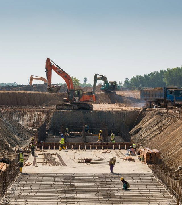 A close shot of heavy machines and construction workers working on a building